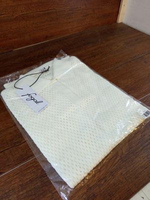 une serviette blanche emballée dans du plastique, posée sur un plancher en bois