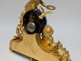 a gold clock with an angel on top of it