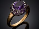 a close up of a gold ring with a purple stone
