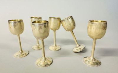 six silver goblets are lined up in a row on a white surface