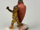 a statue of a boy holding a vase on a marble base