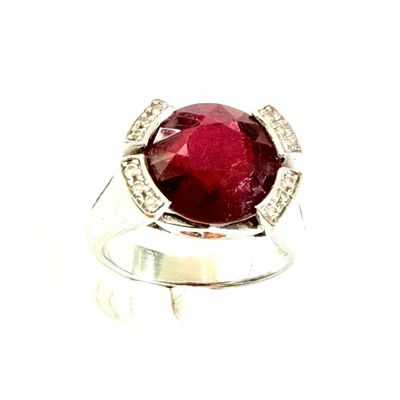 une image représentant une bague ornée d'une grosse pierre rouge entourée de diamants