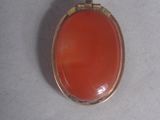 an image of a pendant with a red stone on a white string