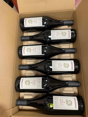 six bottles of wine are in a cardboard box on a table