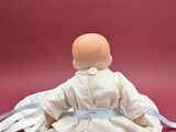 a doll that is sitting on the ground with a ribbon around it