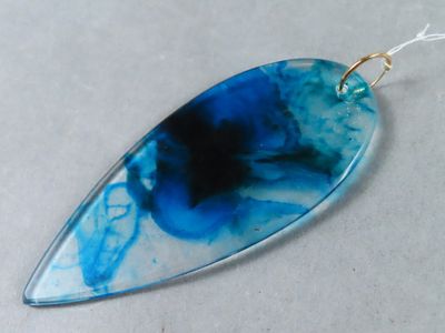 Le pendentif est en verre et présente un motif bleu et noir.