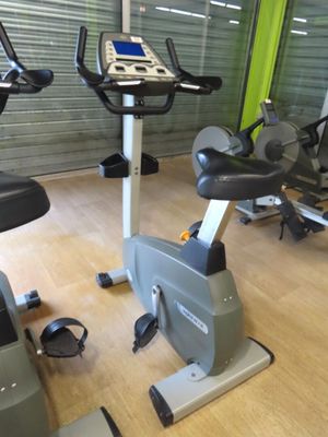 a gym room with a row of stationary exercise bikes