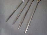 three antique silverware spoons and a pair of scissors on a gray cloth