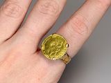 someone is holding a ring with a gold coin on it