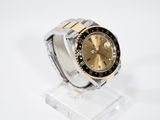 an image of a watch with a gold dial and black bezel