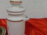 a white vase and a plate on a red table cloth