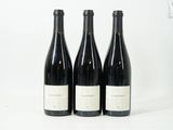 trois bouteilles de vin sont alignées sur une surface blanche
