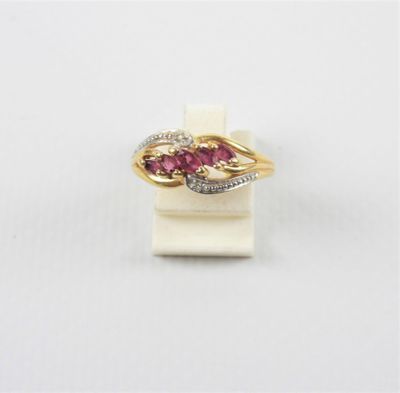 un gros plan d'une bague en or sertie de pierres roses sur un fond blanc