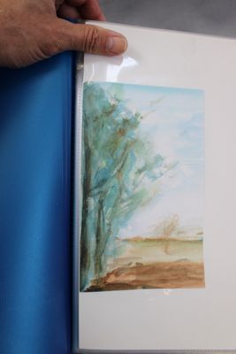 a person holding a book with a painting on it