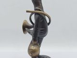 statue en bronze représentant un canard tenant une trompette, sur fond blanc