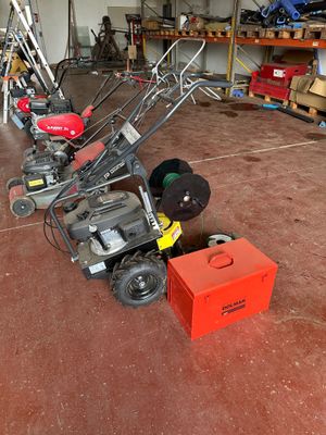 several lawn mowers are lined up in a garage