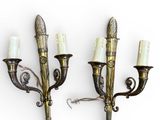 pair of brass wall sconces with white candles on each of them
