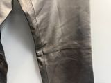 un pantalon en cuir sur un cintre, à côté d'une paire de chaussures