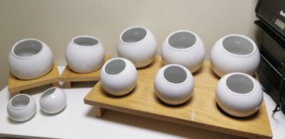 six white vases sitting on a wooden tray next to a printer