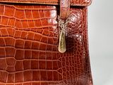 a brown alligator skin bag with a gold clasp