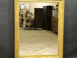 a large gold framed mirror on the floor in a room