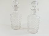 two clear glass bottles sitting next to each other on a white surface