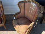 pair of antique chairs with upholstered cushions in front of a garage door