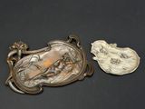 une assiette en argent avec une image dessus, à côté d'une assiette en argent avec une image dessus