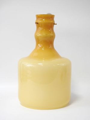a yellow glass bottle sitting on a white surface