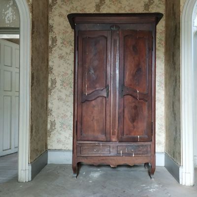 une vieille armoire en bois dans une pièce dont l'un des murs est tapissé