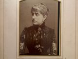 an old photo of a woman in a black dress in a white frame