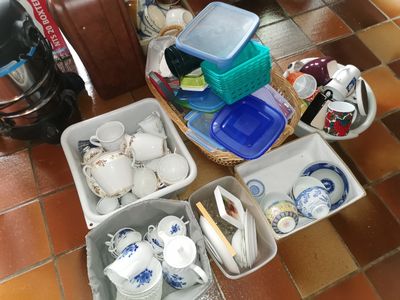 un panier rempli d'assiettes et de tasses posé par terre