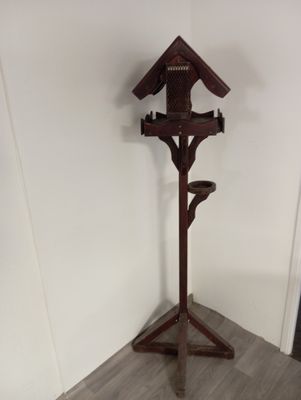 un nichoir en bois posé sur un socle dans un coin de la pièce