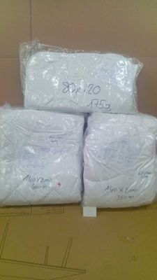 trois sacs contenant des couvertures blanches sont empilés sur une boîte en carton