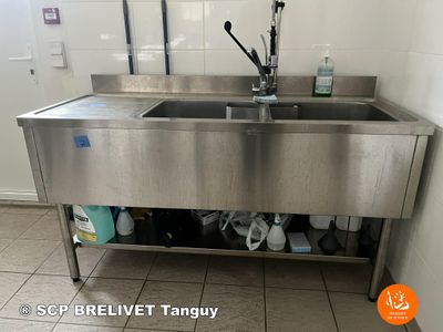 a stainless steel sink in the corner of a bathroom