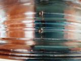 a close up view of a glass vase with a reflection of a person in the background