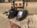 two welding helmets sitting on a table in a factory