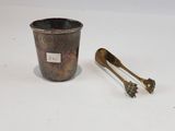 a silver cup with a spoon next to it on a white surface