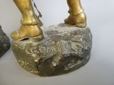 une statue en bronze représentant un homme assis sur un rocher