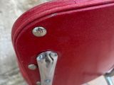 a red suitcase sitting on a chair in front of a stone wall