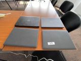 quatre ordinateurs portables posés sur une table dans une salle de réunion