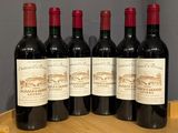 four bottles of wine are sitting on a wooden barrel