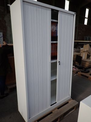 a tall white cabinet with a sliding door next to a pallet