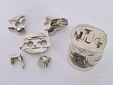 several pieces of silver metal on a white surface