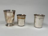 trois tasses en argent posées l'une à côté de l'autre sur une surface blanche