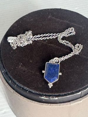 un collier orné d'une pierre bleue, présenté dans un coffret noir