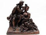 une statue en bronze représentant un homme et une femme assis sur un rocher
