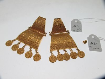 deux paires de boucles d'oreilles en or et une étiquette de prix posée sur une table