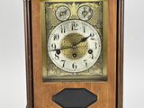 une horloge en bois posée sur une surface blanche