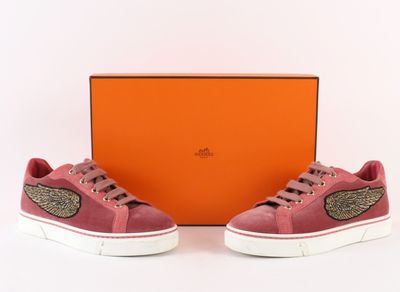 une paire de baskets roses avec des détails dorés et une boîte